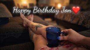 Coffee cup resting on tattooed legs 